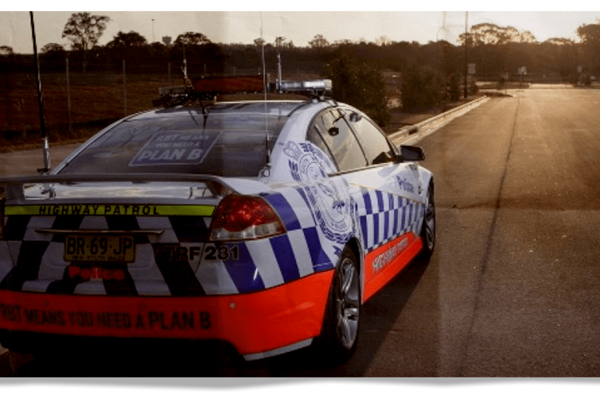 The rear end of a police highway control car on a suburban street at sunset