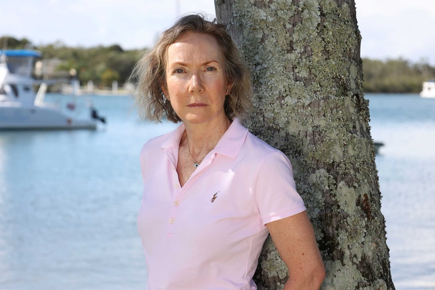 Michelle Snape stands in front of a river, looking at the camera.