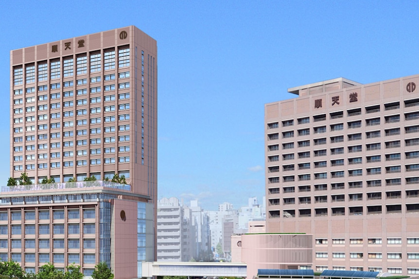 Juntendo University buildings are surrounded by high rise buildings in Tokyo on a sunny day with trees framing the image.