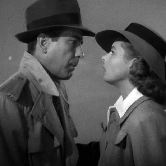 A black and white still from Casablanca, featuring a man and a woman in black hats staring intently into each other's faces.