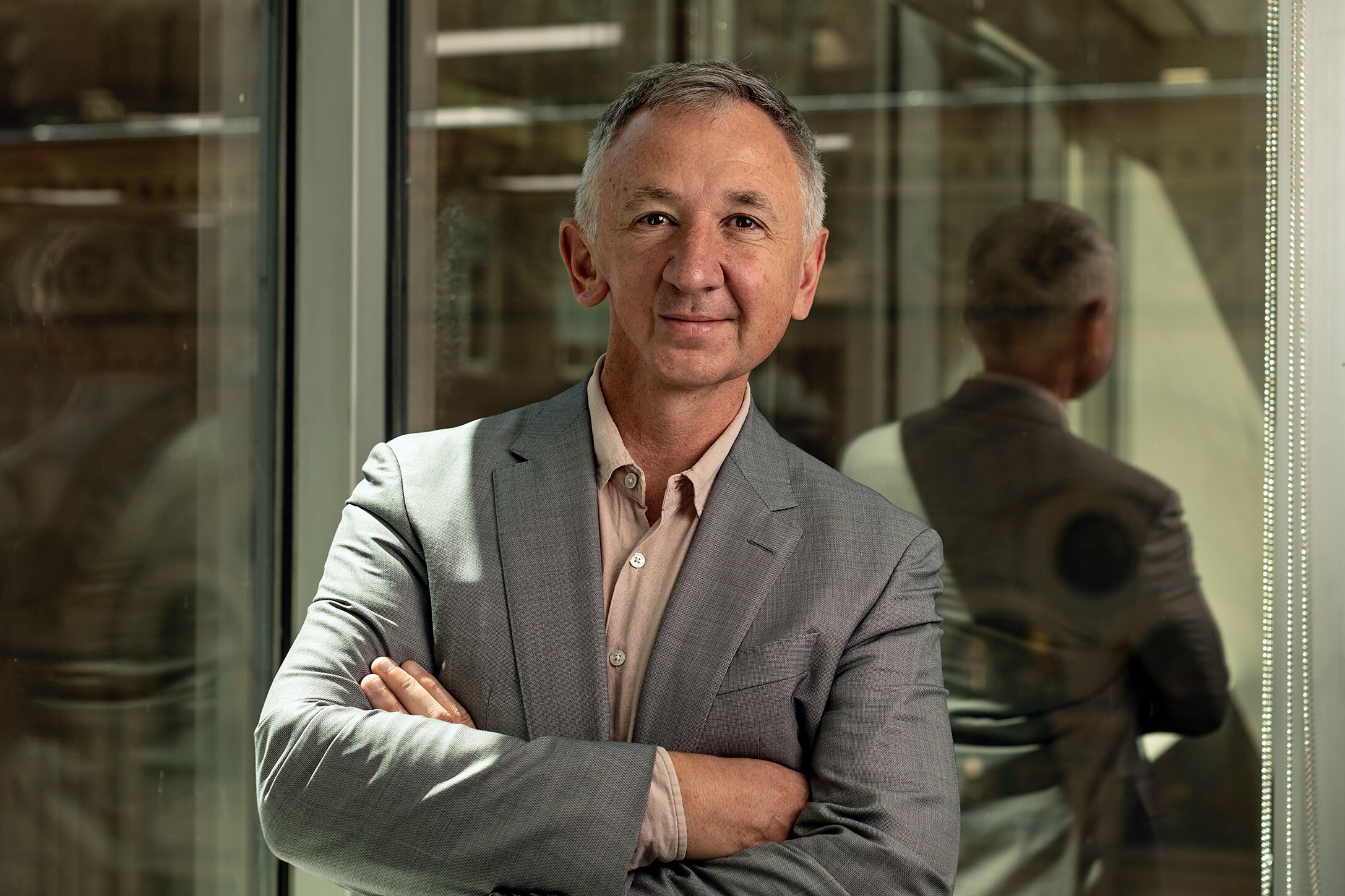 A man wearing a grey suit stands in a lab