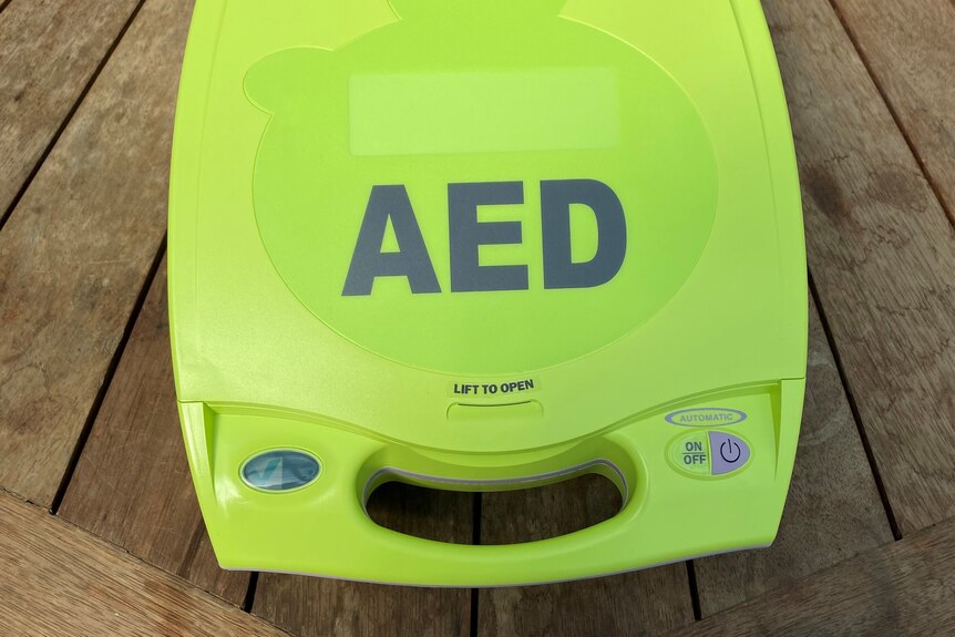Green fluro defibrillator or AED on a wooden table.
