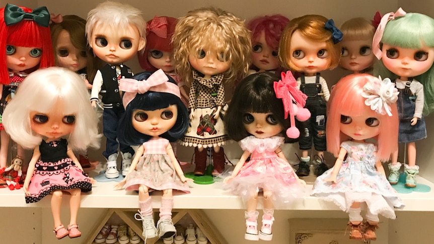 14 dolls arranged on a shelf