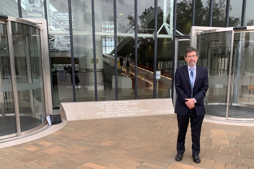 A man with grey hair wearing a suit stands outside the High Court of Australia