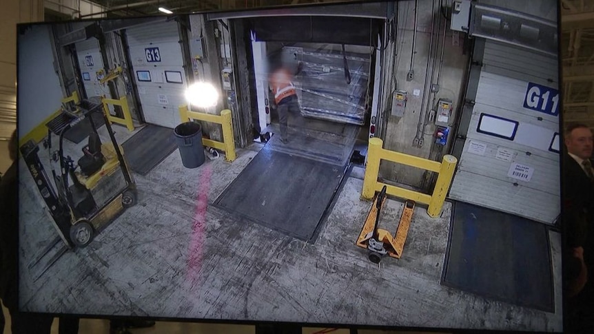 CCTV vision of a man loading a pallet  of boxes into a truck from a warehouse.