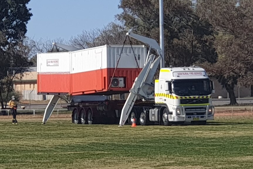 A demountable building being put up in a field.