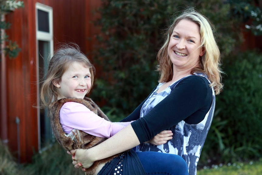 A daughter hugs her mother both smiling