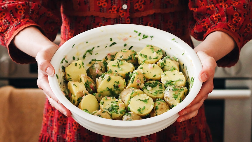 Serving bowl of potato salad with chives and shallot, a summer salad to bring to festive feasts.