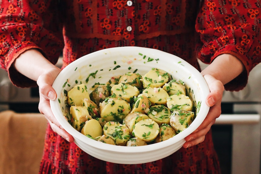 Serving bowl of potato salad with chives and shallot, a summer salad to bring to festive feasts.