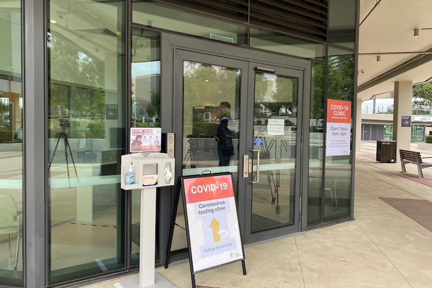 Signs and posters displayed near the doors of a hospital entrance.