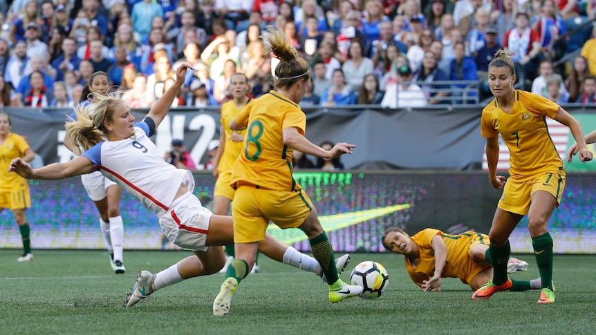 Lindsey Horan reaches for the ball with her foot while Elise Kellond-Knight runs with it.