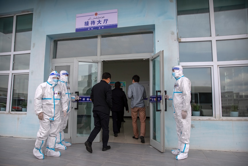 Security officers in protective suits hold the doors as government officials enter the visitors' hall
