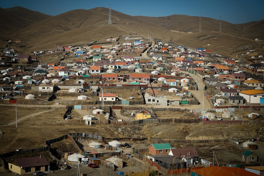 Rows of houses are dotted along a hillside, connected by dirt roads