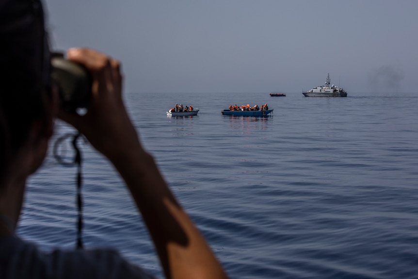 Three small boats and a coast guard vessel.