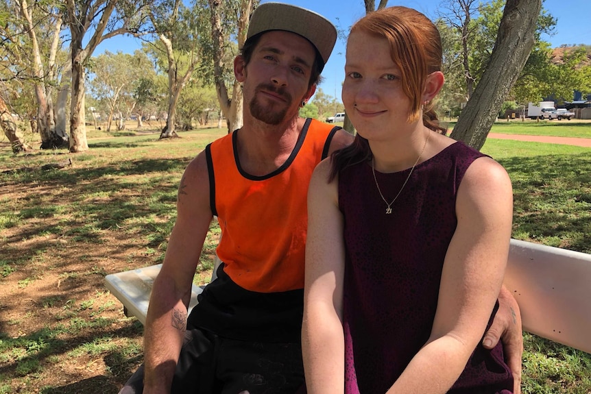 Tayla Smedley sits with her partner on a park bench.