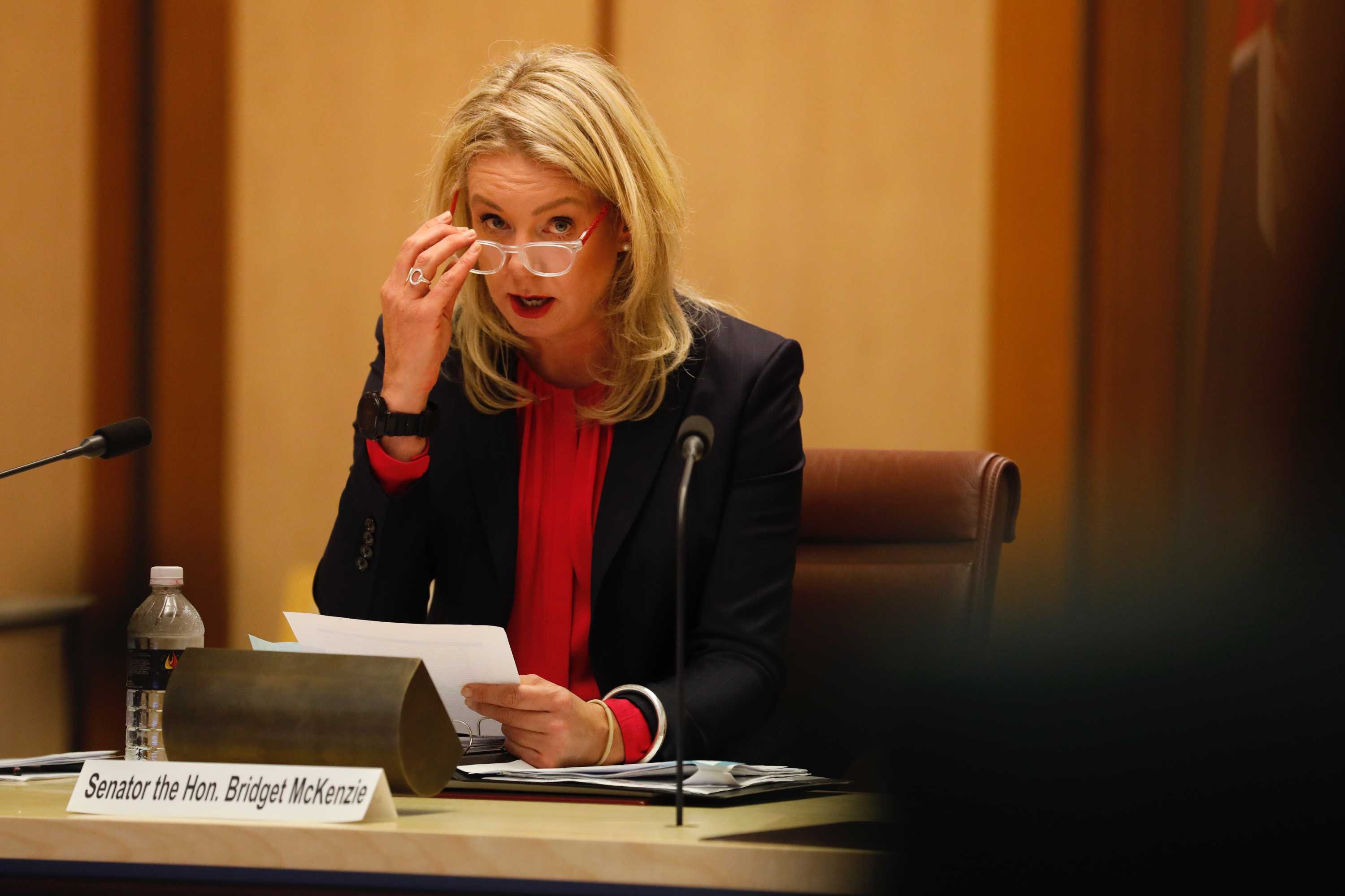 Bridget McKenzie sits at a table answering questions in a wood-panelled room