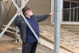 A man with a hat pointing to a line on a metal pole
