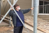 A man with a hat pointing to a line on a metal pole