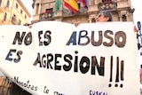 People hold up a huge white sign which says "No es abuso, es agresion!"