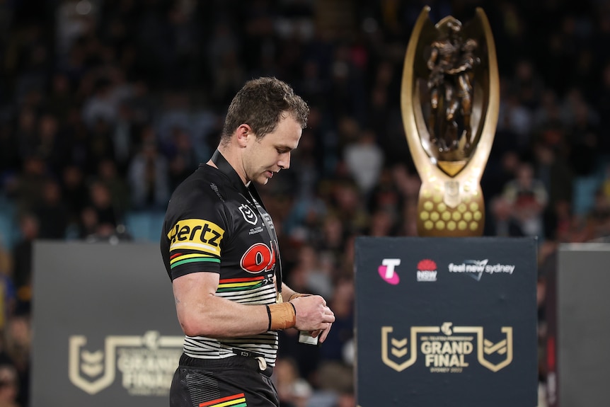 Dylan Edwards looks down as he walks past the NRL grand final trophy after receiving the Clive Churchill Medal.