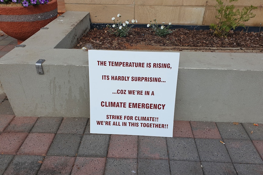 A sign drawing attention to a climate change emergency near where Ariel Ehlers was sitting.