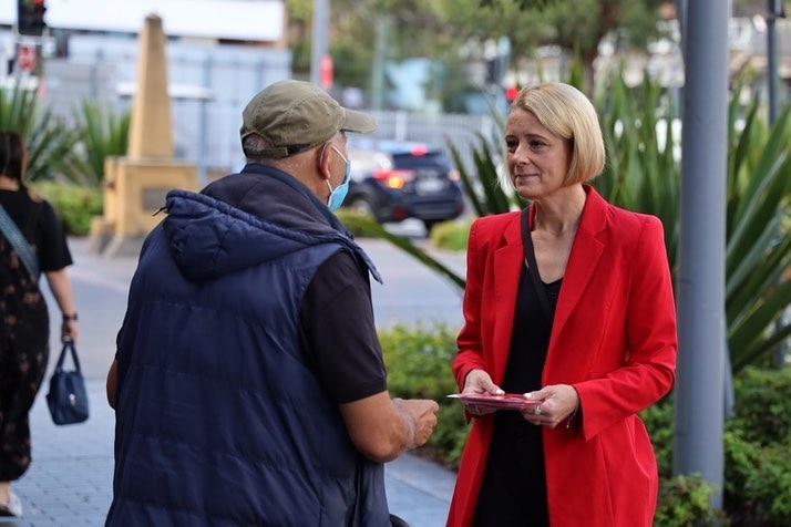 a woman talking to an elderly man on the street