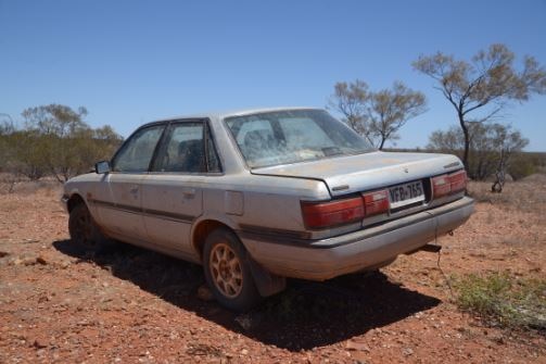 A silver sedan parked on the dirt next to a remote highway in South Australia