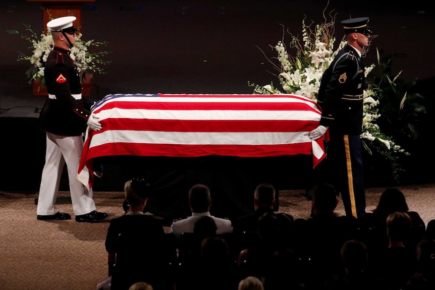 John McCain's casket, draped in the American flag, is lead out of a memorial service.