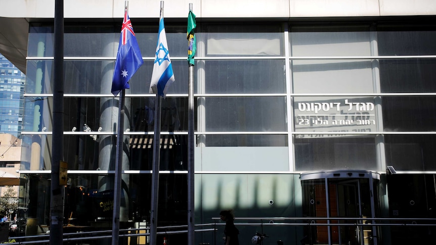 The Australian and Israeli national flags hang outside a grey building.