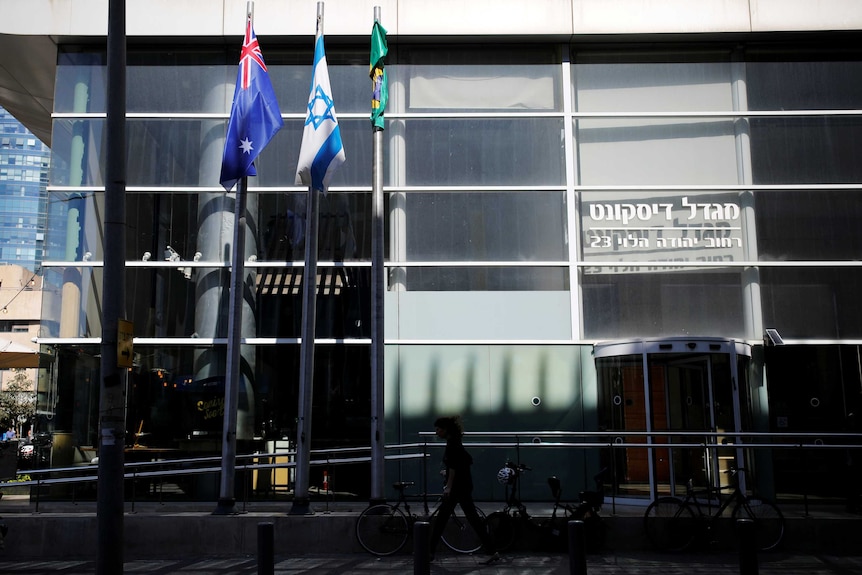 The Australian and Israeli national flags hang outside a grey building.
