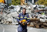NZ quake: a Qld rescue worker walks past the rubble of the CTV building