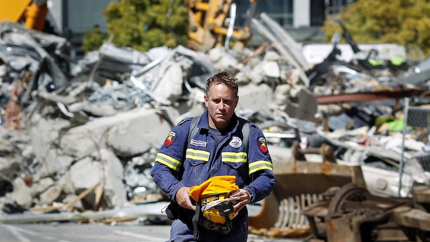 NZ quake: a Qld rescue worker walks past the rubble of the CTV building