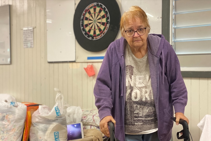 a woman with a walker looks at the camera with a sombre expression