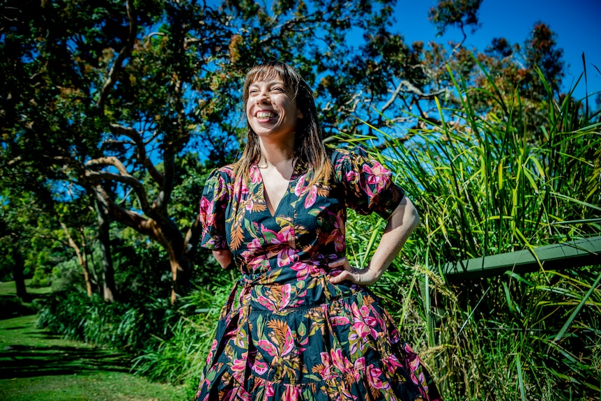 A smiling woman with a floral dress in the sunshine