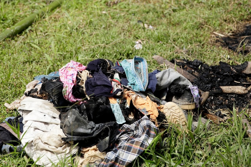 A pile of burned clothes lying on the grass.
