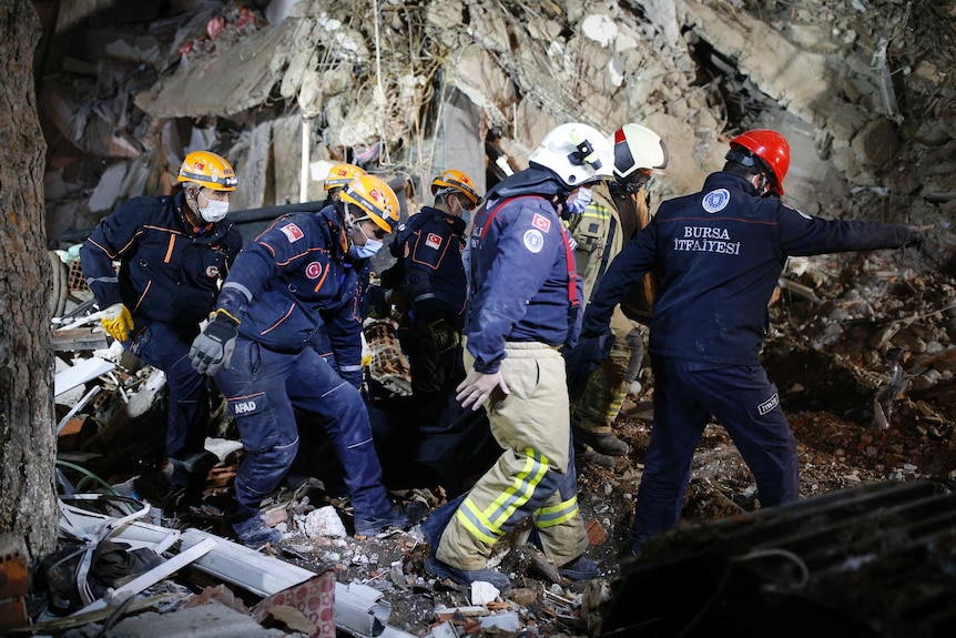 Members of rescue services carry a body of a victim from the debris of a collapsed building in Izmir.