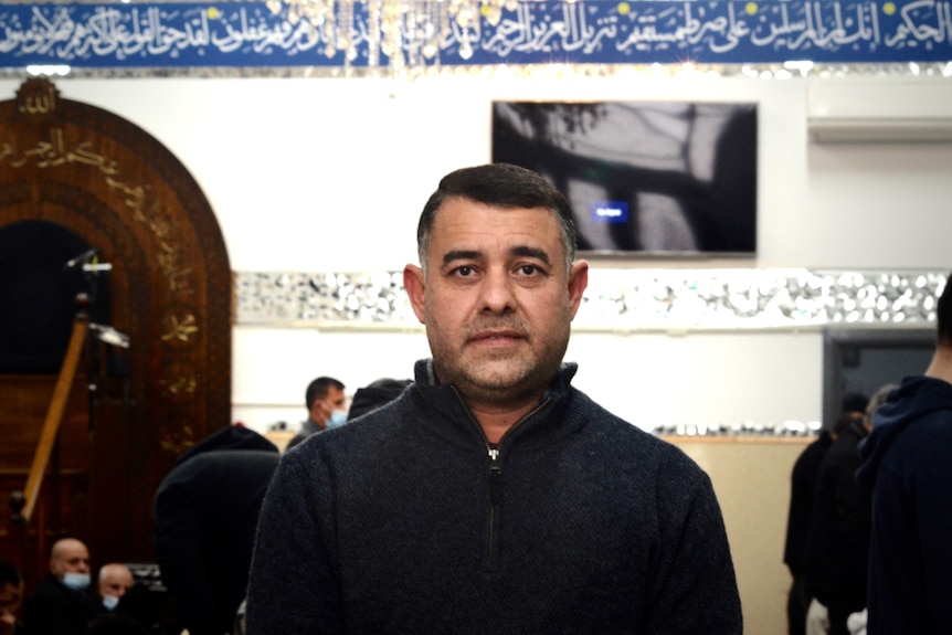 A photo of Hassan standing in front of worshipers at the Ahulalbait mosque.