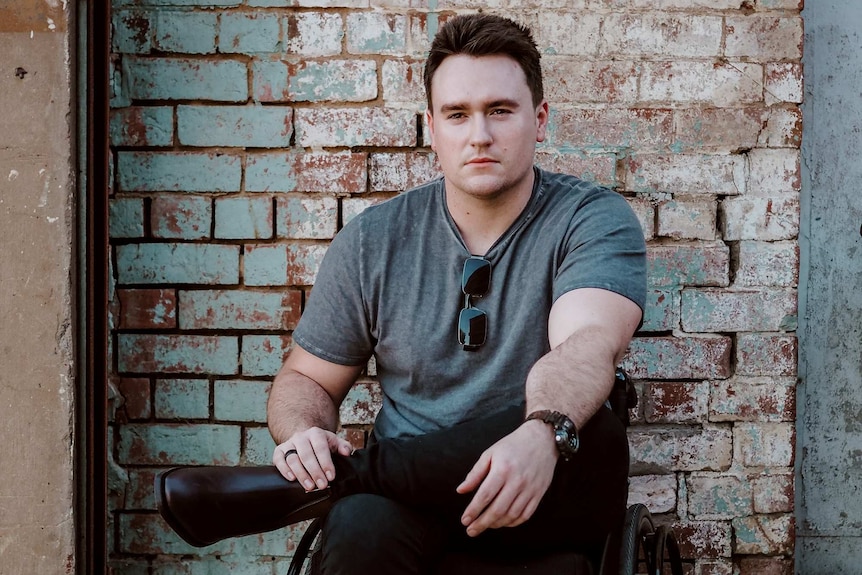 A photograph of model and wheelchair user Jason Clymo in front of a brick wall.