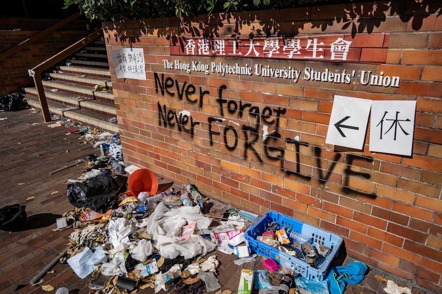 Rubbish lies in front of a wall that reads "never forgive, never forget".