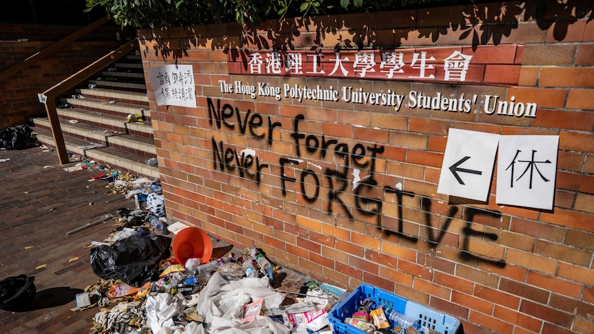 Rubbish lies in front of a wall that reads "never forgive, never forget".