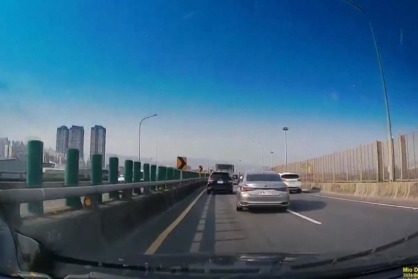 Screengrab of dashcam video of three cars on a multi-lane highway. 