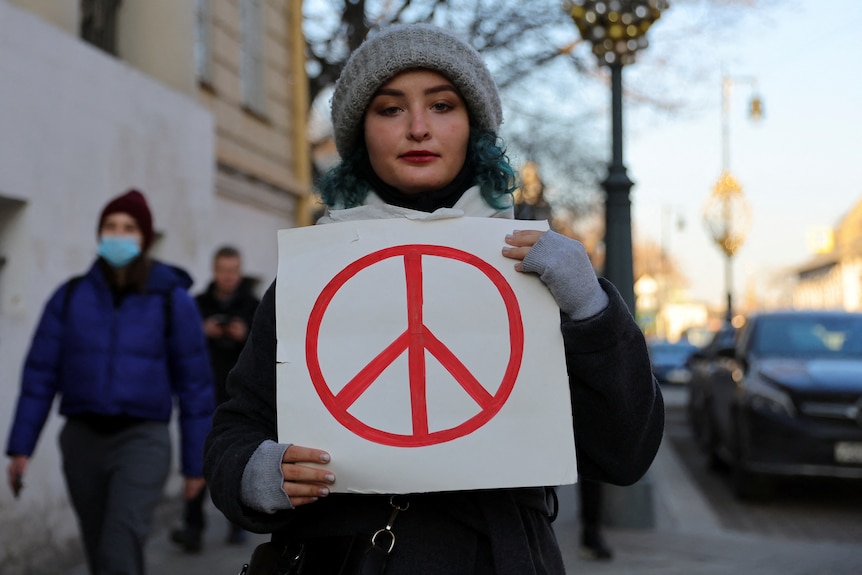 Człowiek trzyma sztandar podczas protestu przeciwko rosyjskiej inwazji na Ukrainę