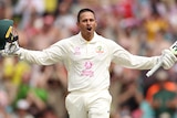 Usman Khawaja stands with his arms outstretched with a smile on his face