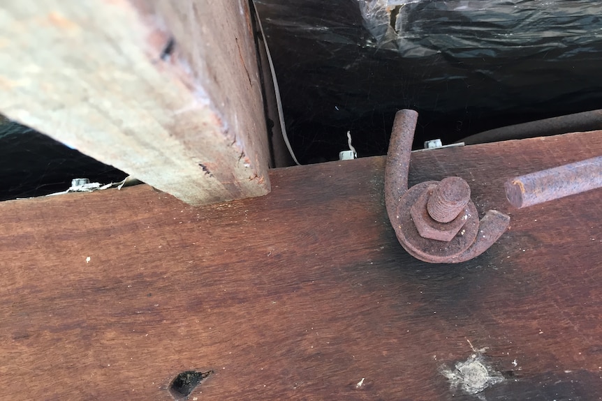 a roof beam with a bolt and iron rod that's been grinded in half
