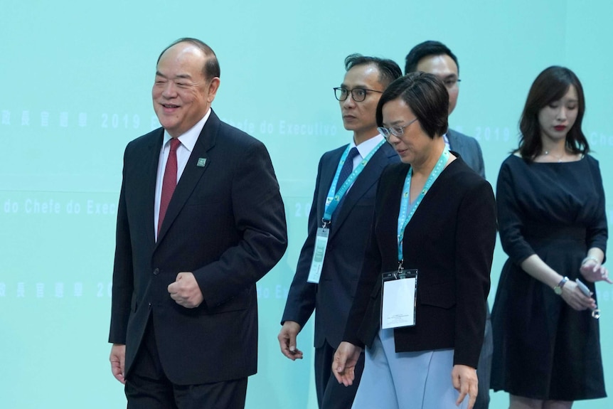 Ho Iat Seng, far left, walks in front of a group of people.