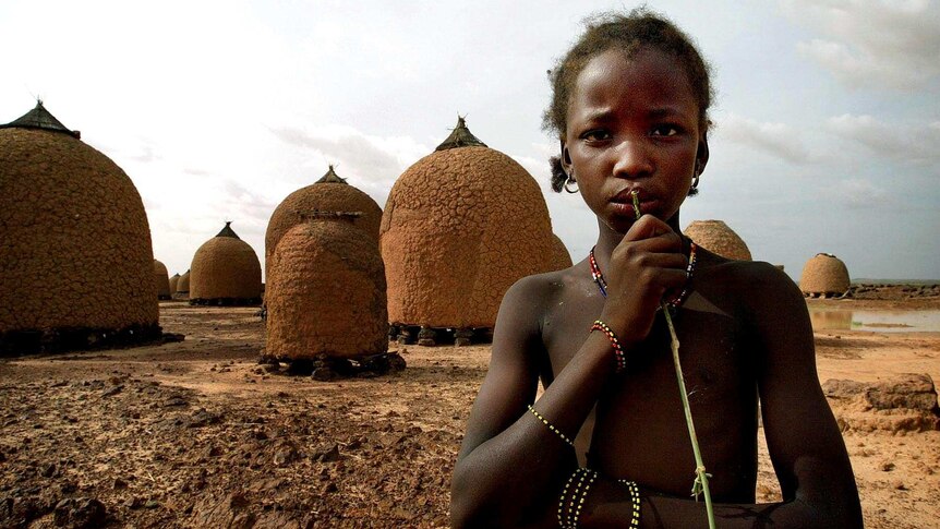 A girl stands in front of empty granaries at the Tangaba village in Niger