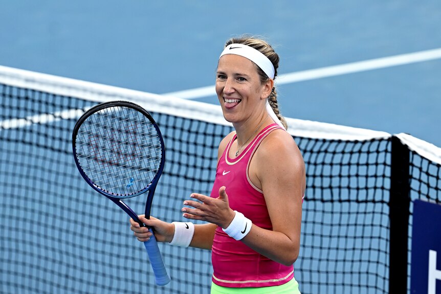 Tennis star Victoria Azarenka smiles and sticks her tongue out in celebration on court after winning a match.