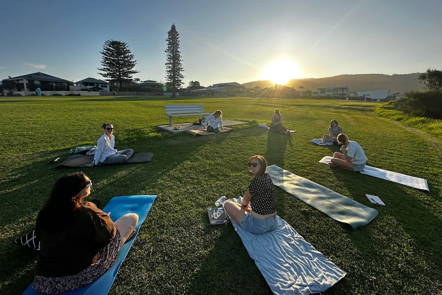 Women practising yoga in a park