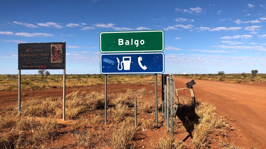 A dirt road with a sign saying Balgo