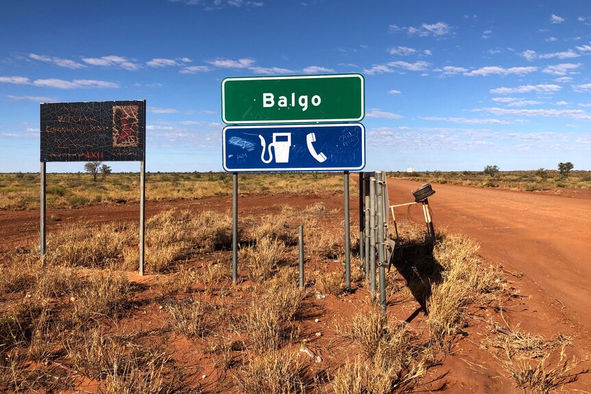 A dirt road with a sign saying Balgo